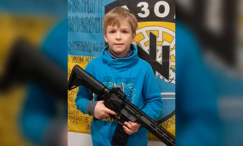 Niño con fusil posa frente a un símbolo nazi en un video de propaganda ucraniana
